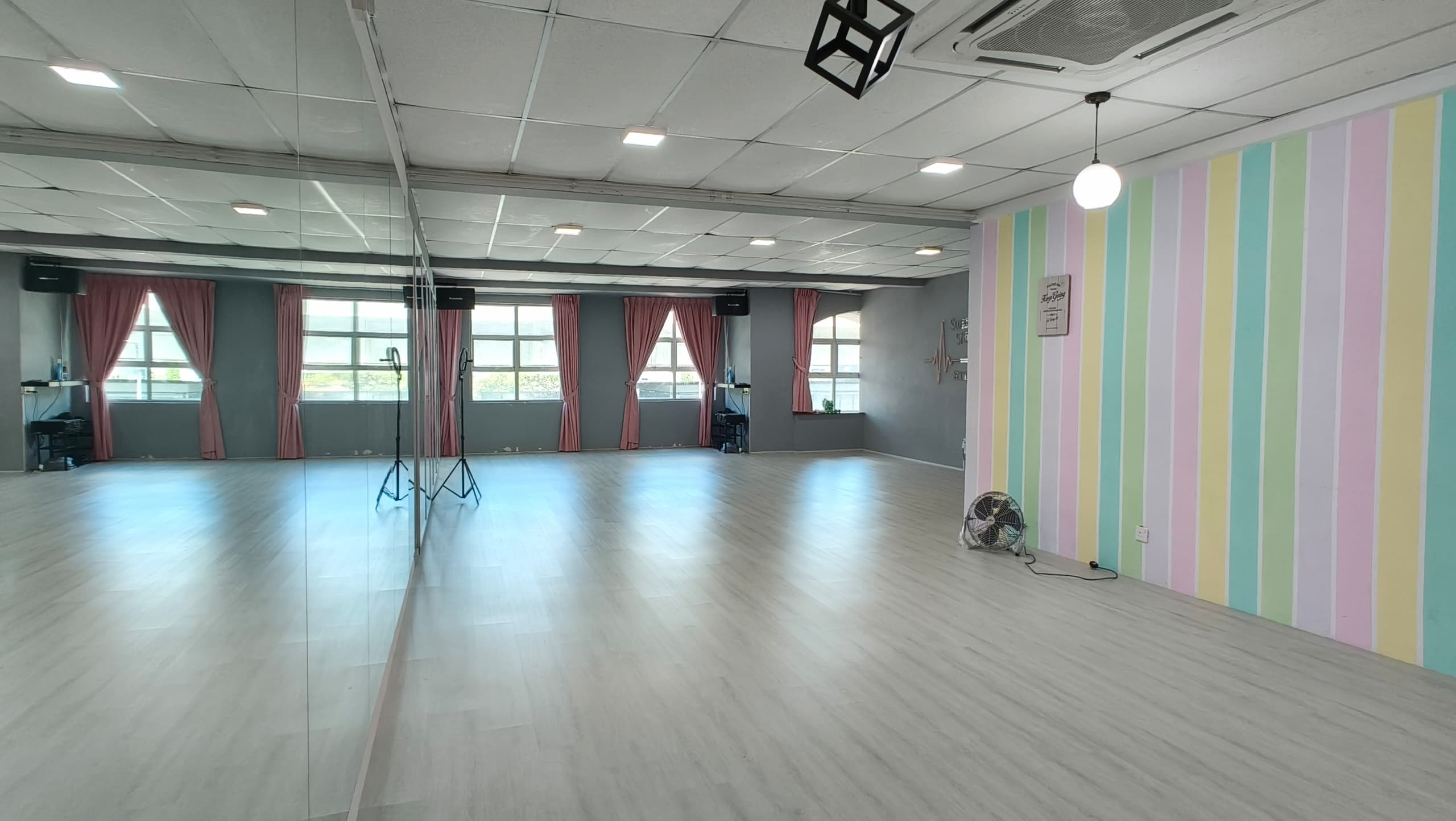 Meet In Studio dance floor in daylight — full-length mirrors, pastel stripe wall, hardwood floors in Kuala Lumpur